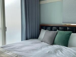 Una cama con almohadas verdes y blancas. en Mu Ju B&B, en Magong