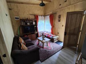 a living room with a couch and a table and a television at Cabañas Koyam in Melipeuco