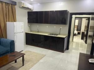 a kitchen with black cabinets and a white refrigerator at Admire Apart Hotel - 1 in Abu Arish