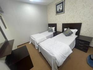 a hotel room with two beds with white sheets at Admire Apart Hotel - 1 in Abu Arish