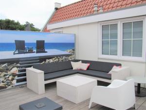 a patio with a black and white couch and chairs at Luxury apartment in Koudekerke with sauna in Koudekerke