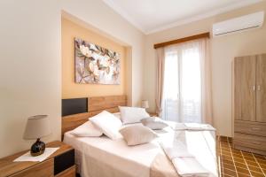 a bedroom with a bed with white sheets and a window at Joya Zante city apartment in Zakynthos Town