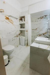 a white bathroom with a toilet and a sink at Hermes Appartment in Chalkida