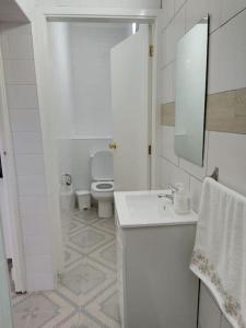 a white bathroom with a toilet and a sink at Rua de Baixo Apartments in Calheta