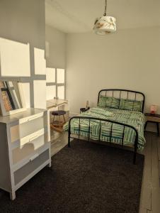 a bedroom with a bed with a green comforter at Philippa Court Grade II townhouse- 3 bedrooms- free parking in Norwich