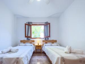 two beds in a room with a window at Can Pep Yern 2 in Playa Migjorn