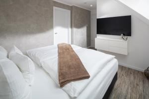 um quarto com uma cama branca e uma televisão de ecrã plano em Salt and Sea em Norderney