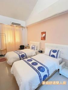 2 camas en una habitación de color blanco y azul en Dear B&B Building II, en Jincheng