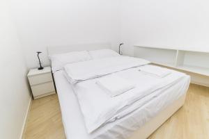 Cama blanca con sábanas y almohadas blancas en City Castle Apartments Free Parking en Bratislava