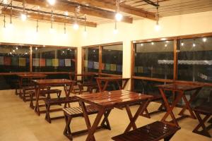 a row of wooden tables and benches in a room at Pinaceae Resort in Chakrāta