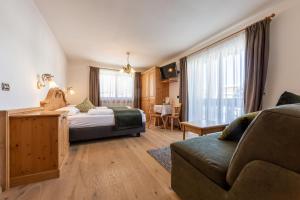 ein Hotelzimmer mit einem Bett und einem Sofa in der Unterkunft B&B Grüne Laterne - Lanterna Verde in Sexten