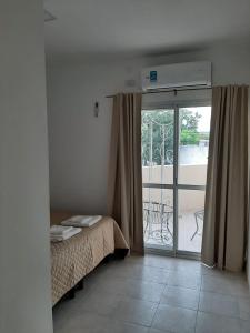 - une chambre avec un lit et une porte coulissante en verre dans l'établissement Junín Dptos 2, à San Fernando del Valle de Catamarca