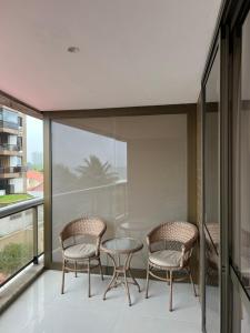 Duas cadeiras e uma mesa de vidro numa varanda em Apart suite frente ao mar no Rio de Janeiro