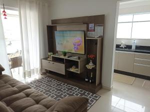 a living room with a couch and a flat screen tv at Apto temporada Itapema sc in Itapema
