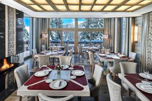 a dining room with tables and chairs and a fireplace at Lys Martagon in Courchevel
