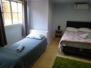 1 dormitorio con 2 camas y 2 ventanas en Casa dos Pinheiros I, en Gramado