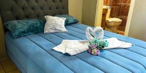 Una cama azul con toallas y un conejo relleno. en Casa dos Pinheiros I, en Gramado