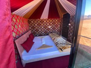 a bed in a tent with red pillows at Desert shine camp in Wadi Rum