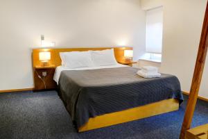 Peach Hostel & Suites في بورتو: غرفة نوم بسرير كبير مع طاولتين ومصباحين