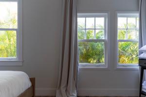 1 dormitorio con 3 ventanas y 1 cama con cortinas en The Grandview Collection - FL Ave en West Palm Beach