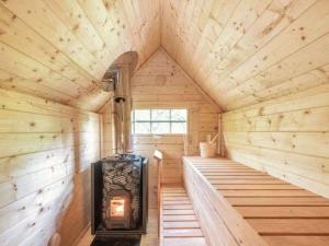 a wooden sauna with a stove in the middle at Treetops Luxury Log Cabin - Hot tub, BBQ & Sauna in Kippford