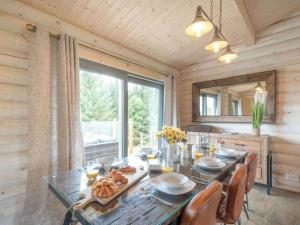 a dining room with a table and a large window at Treetops Luxury Log Cabin - Hot tub, BBQ & Sauna in Kippford