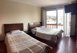 2 bedden in een hotelkamer met een raam bij ALOJAMIENTOS HOSTAL REST HOUSE in Cuenca