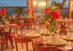 un restaurante con mesas y sillas con flores rojas. en PSP Resort All Inclusive, en Porto Seguro