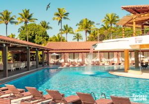 uma piscina num resort com cadeiras e palmeiras em PSP Resort All Inclusive em Porto Seguro