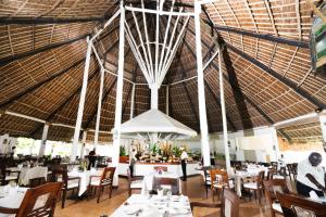 a restaurant with white tables and chairs and a large ceiling at Sandies Malindi Dream Garden in Malindi