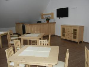 a dining room with tables and chairs and a flat screen tv at Guesthouse Macesen in Spodnja Sorica