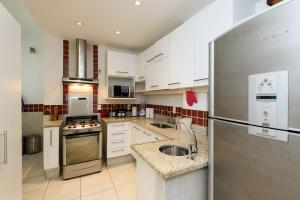 a kitchen with white cabinets and a stainless steel refrigerator at 2 Quartos/ 2 banheiros Entre Copa Ipanema Arpoador in Rio de Janeiro