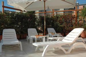 Residence La Casetta في لوانو: مجموعة من الكراسي البيضاء والطاولات ومظلة