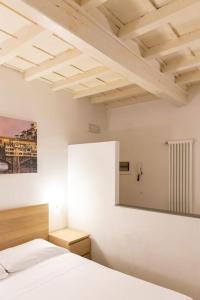 een witte slaapkamer met een bed en een spiegel bij Lovely studio steps from Basilica Santa Croce in Florence