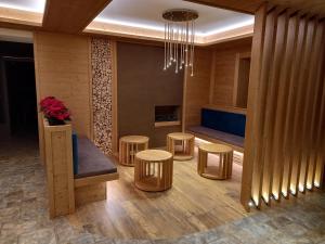 a lobby with a bench and stools and a chandelier at Hotel San Martino in San Martino di Castrozza