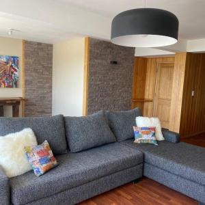 un sofá gris con almohadas en la sala de estar en Hermoso y amplio departamento de categoria en San Carlos de Bariloche