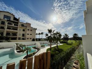 a swimming pool with palm trees and a building at PUSHE Playa Granada Beach & Golf 12 in Motril