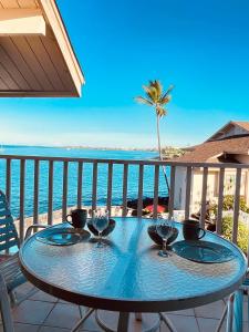 a table on a balcony with a view of the ocean at Unobstructed ocean views, Oceanside Pool, 2B/2B, Sleeps 6 in Kailua-Kona