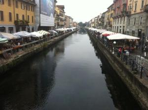 a canal in a city with cars parked on the side at Lovelyloft Navigli - Gelsomino in Milan