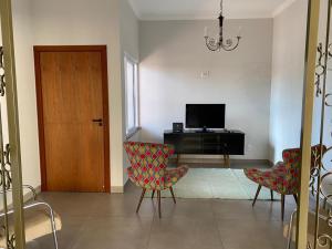 ein Wohnzimmer mit 2 Stühlen und einem TV in der Unterkunft Cantinho Aconchegante 2 in Brotas