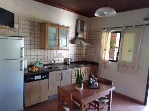 a kitchen with a table and a sink and a refrigerator at Apartamento La Punta in Alojera