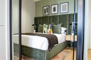 a bedroom with a large bed with a green headboard at Executive Apartment at Ellipse Waterfall in Midrand