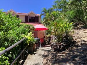 a house with a red umbrella and some plants at A Ka Foufou La in Bouillante
