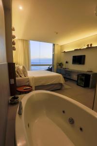 a bathroom with a tub and a bedroom with a bed at Zank by Toque Hotel in Salvador