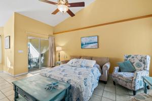 a bedroom with a bed and a couch and a ceiling fan at Heart of the Waves - 3BR & 2BA Beach Retreat - NEW HOT TUB - Outside Patio with Grill & Seating, Steps to Fun! in Melbourne