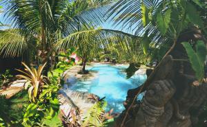 a pool in a garden with palm trees at Paua Hotel Boutique in Pipa
