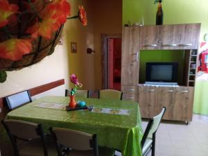 una sala da pranzo con tavolo verde, sedie e televisore di CRISNANBEL a Las Grutas
