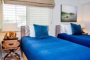 Cette chambre dispose de 2 lits avec des draps bleus et d'une fenêtre. dans l'établissement Serene Hideaway, à Wesley Chapel
