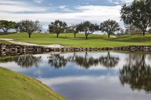 - un parcours de golf avec un étang à côté d'un mur en pierre dans l'établissement Serene Hideaway, à Wesley Chapel