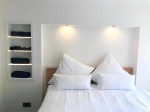 uma cama com lençóis brancos e almofadas num quarto em Hochwertige Wohnung mit Parkplatz im schönen Schwarzwald em Altensteig